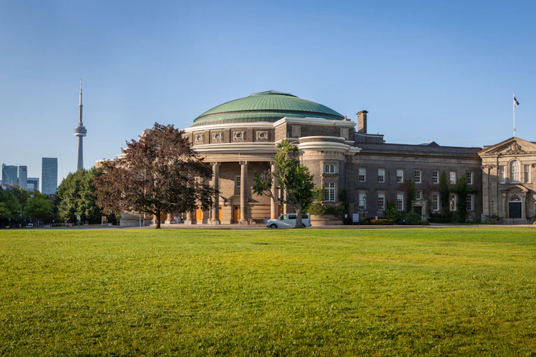 A large building with a green dome. The CN tower is seen in the distance.