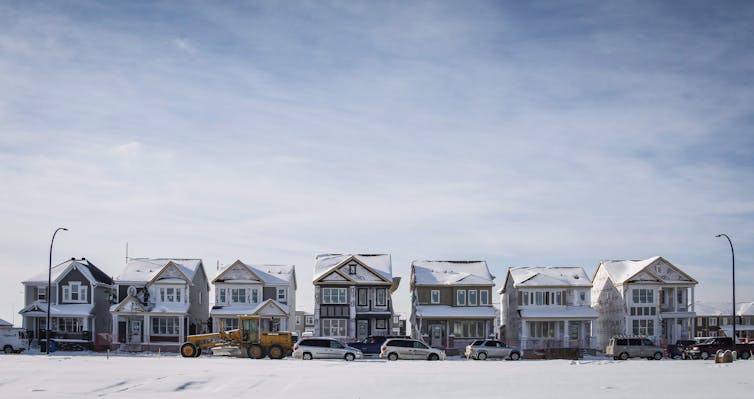 A row of houses under construction under a hazy blue sky.