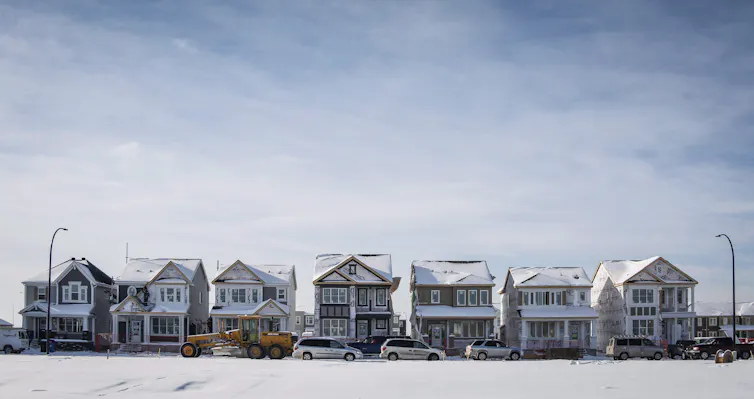 A row of houses under construction under a hazy blue sky.