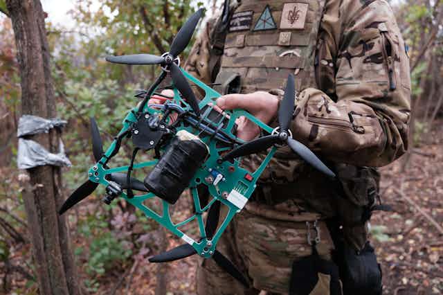 a soldier in the woods holds a crude quadcopter