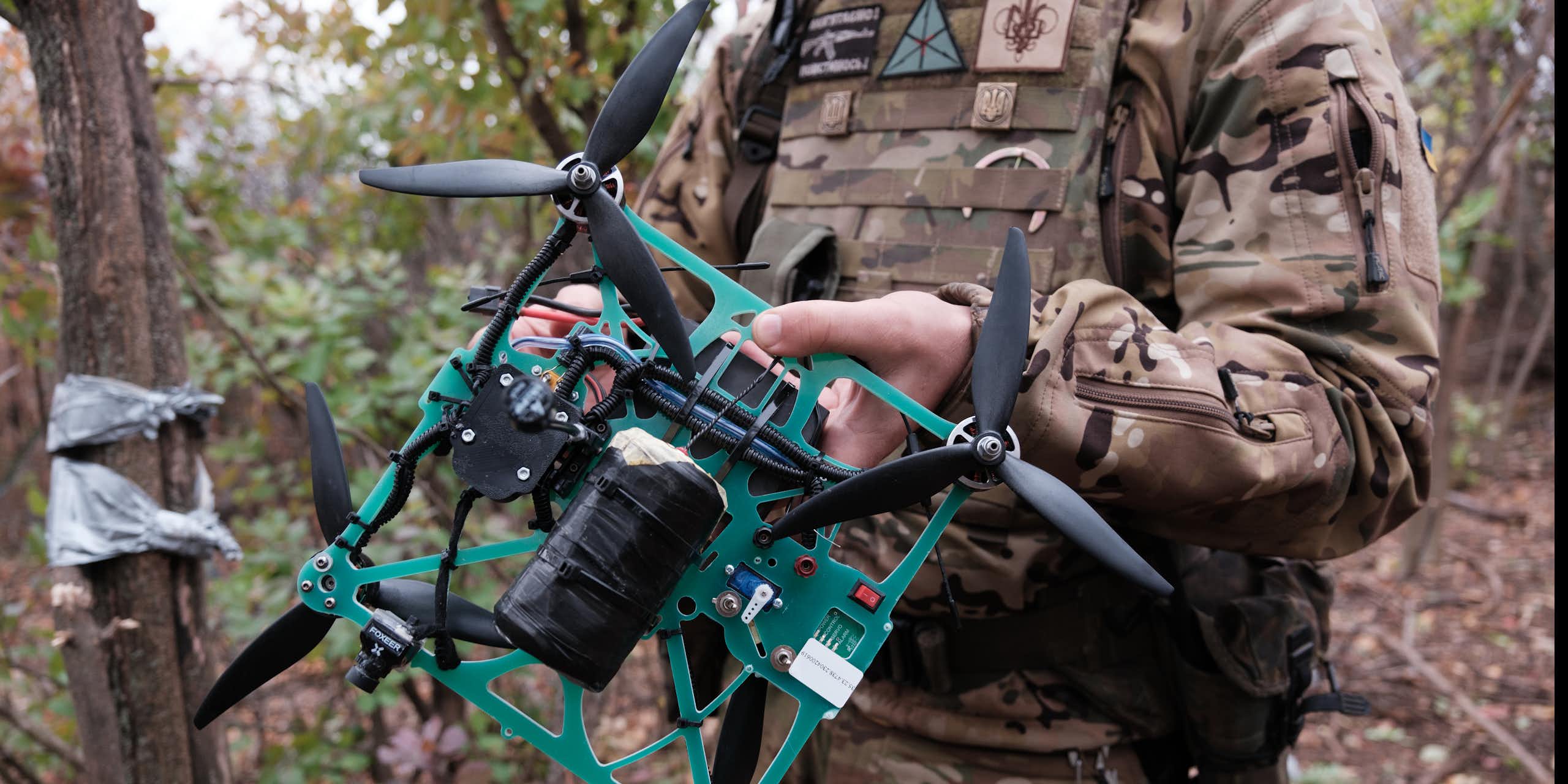 a soldier in the woods holds a crude quadcopter