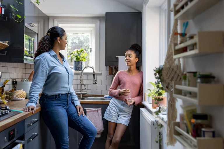 A mother and daughter talk and bond in their kitchen.