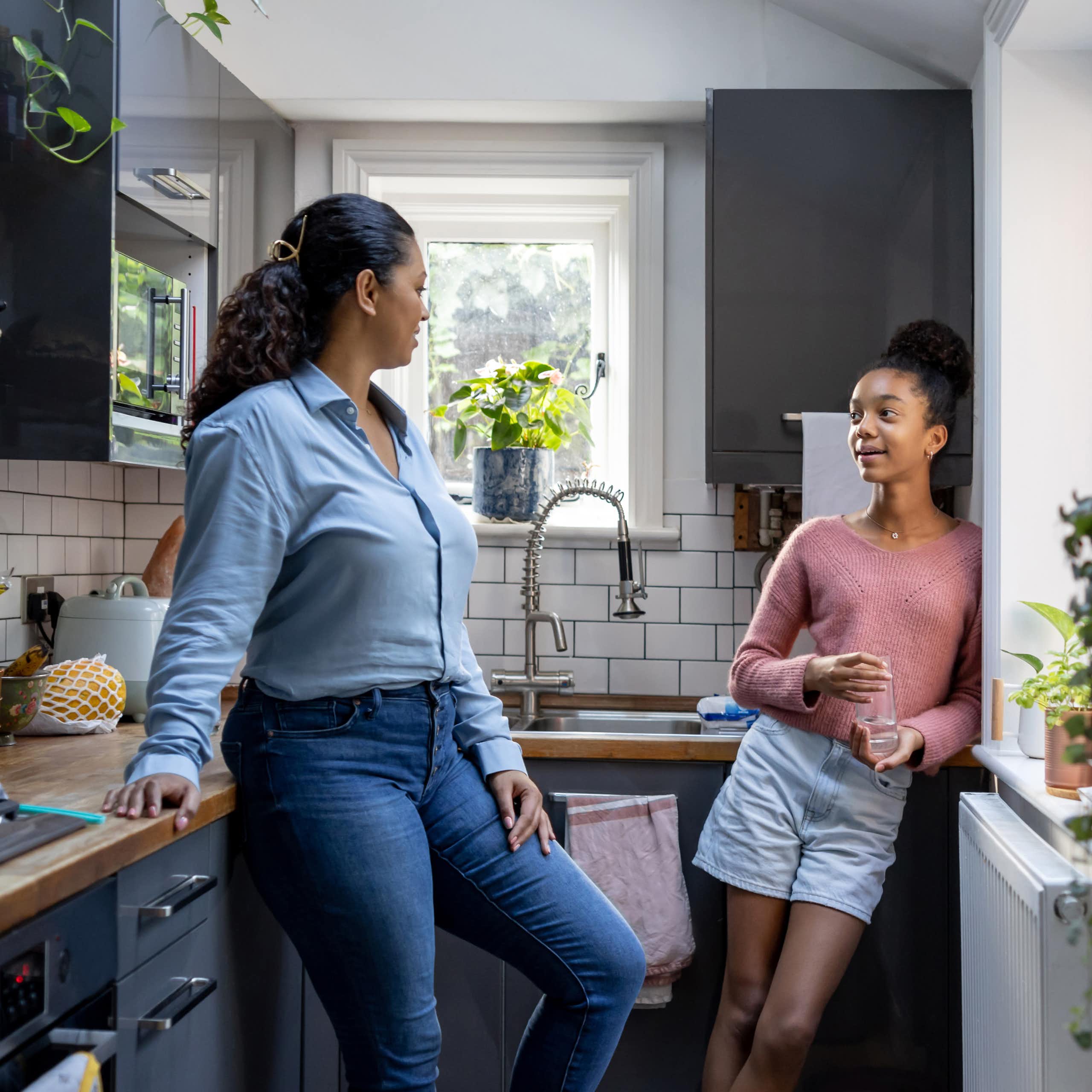 A mother and daughter talk and bond in their kitchen.
