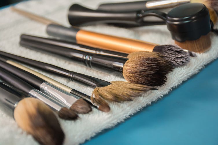 A bunch of makeup brushes are set out to dry on a towel.