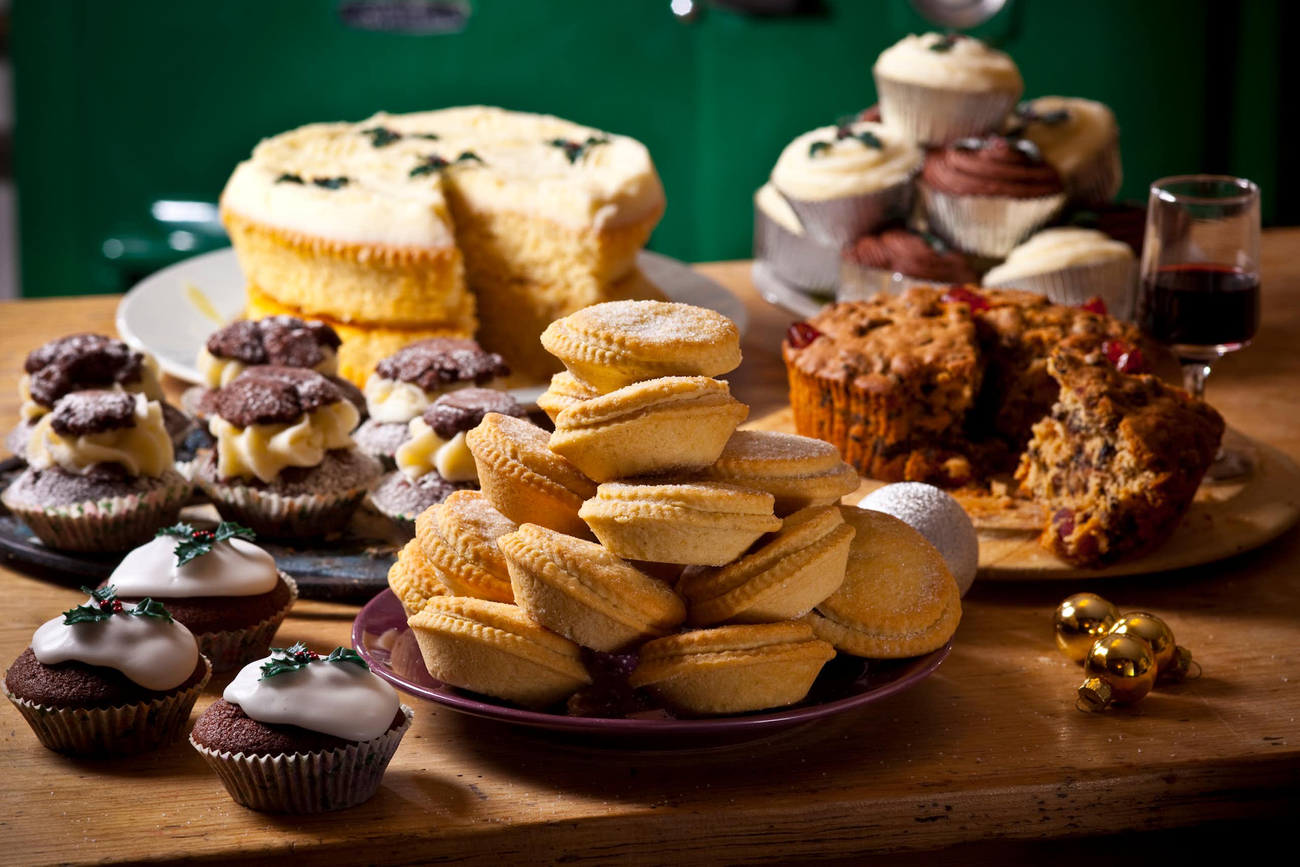 Frosted cupcakes, muffins and sliced cakes are laid out on a table