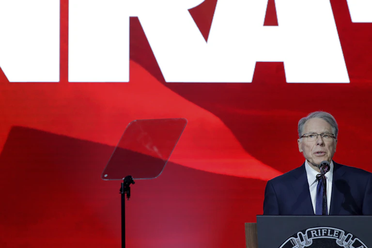 Man in suit and tie stands at a podium under the letters N, R and A.