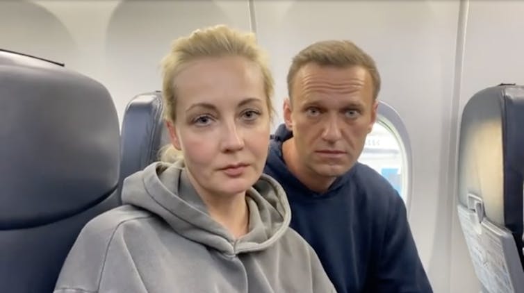 Alexei Navalny and his wife Yulia posemfor a photo sitting on an aircraft.