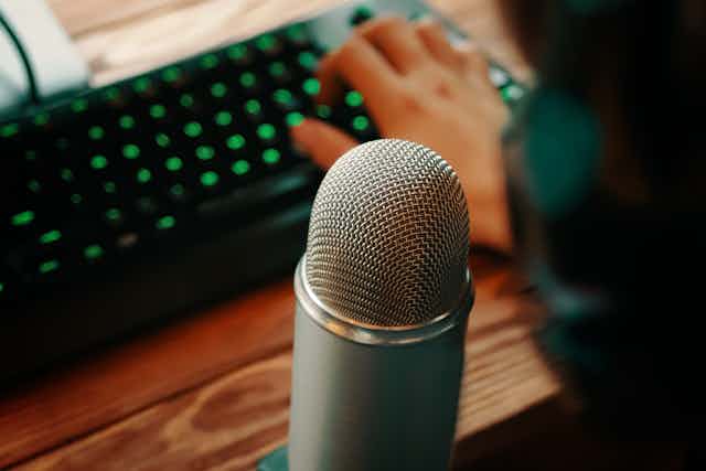 microfone à frente de um teclado de computador operadopor uma mão feminina