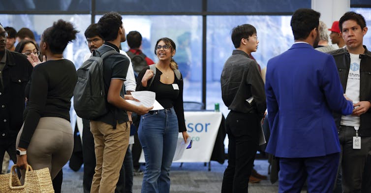 Young people seen milling around tables.