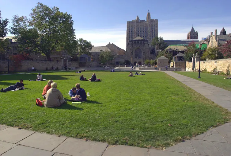 People seen sitting on a campus lawn.