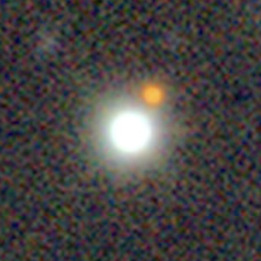 A somewhat noisy photo of a bright white disk and small reddish dot against a dark background.