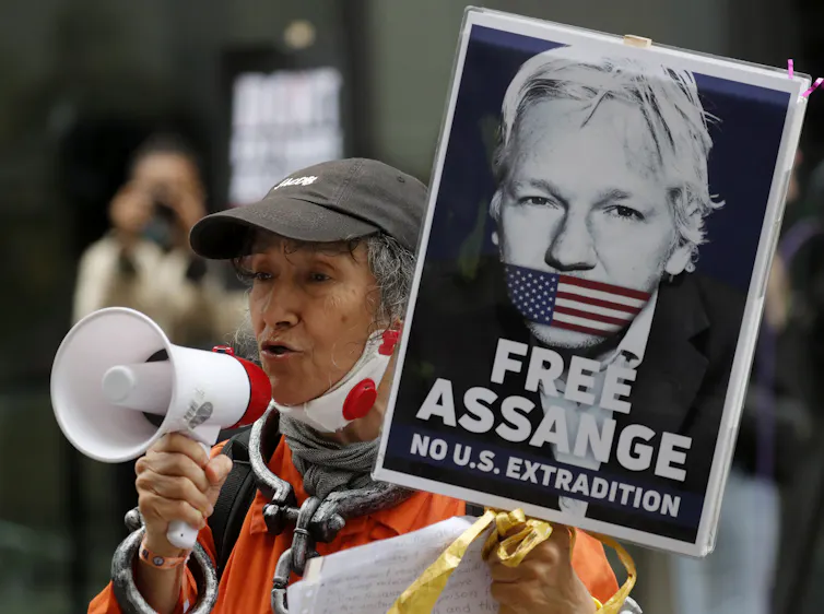 Un manifestante con un megáfono sostiene un cartel de 'liberad a Assange'
