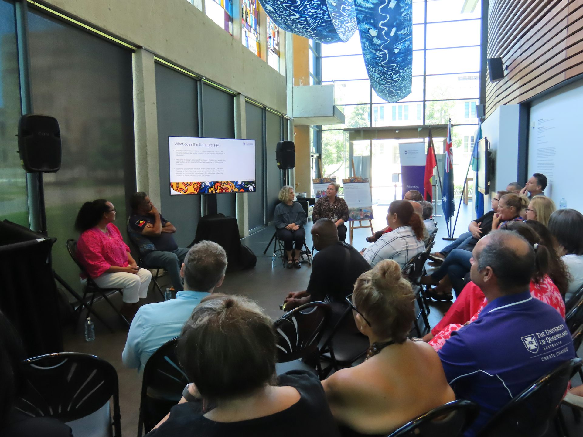 A group of people sit looking at a presentation on a screen.