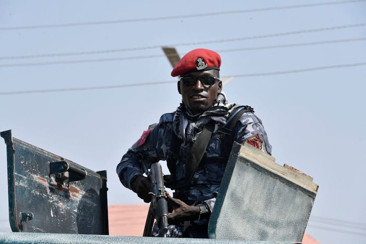 A man in fatigues holding a gun Nigerian police officer stands guard.