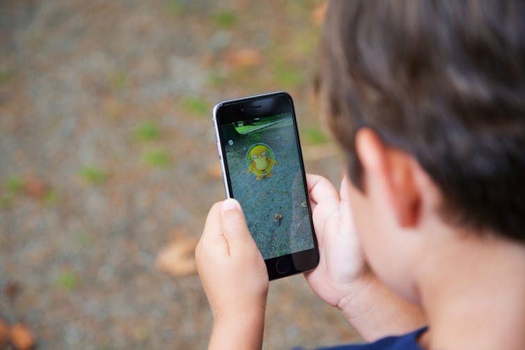 A child holds a mobile phone with Pokemon Go on the screen.