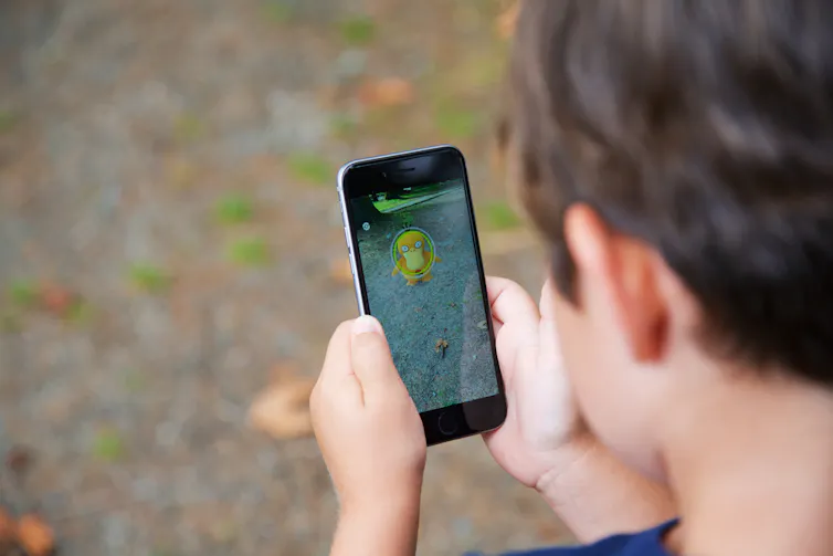 Një fëmijë mban një celular me Pokemon Go në ekran.