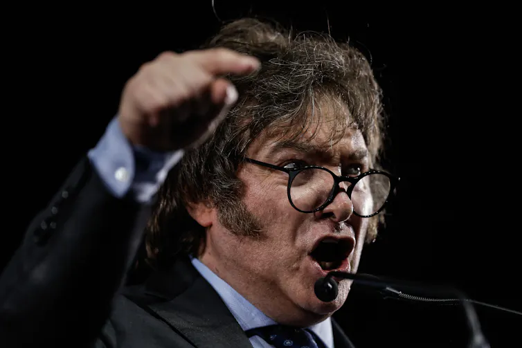 Milei speaking passionately with his arm aloft during a campaign rally.