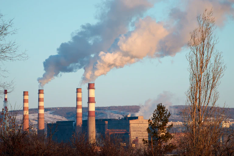 De la fumée sort des cheminées d'une usine pendant une journée ensoleillée, les polluants pénètrent dans l'atmosphère.