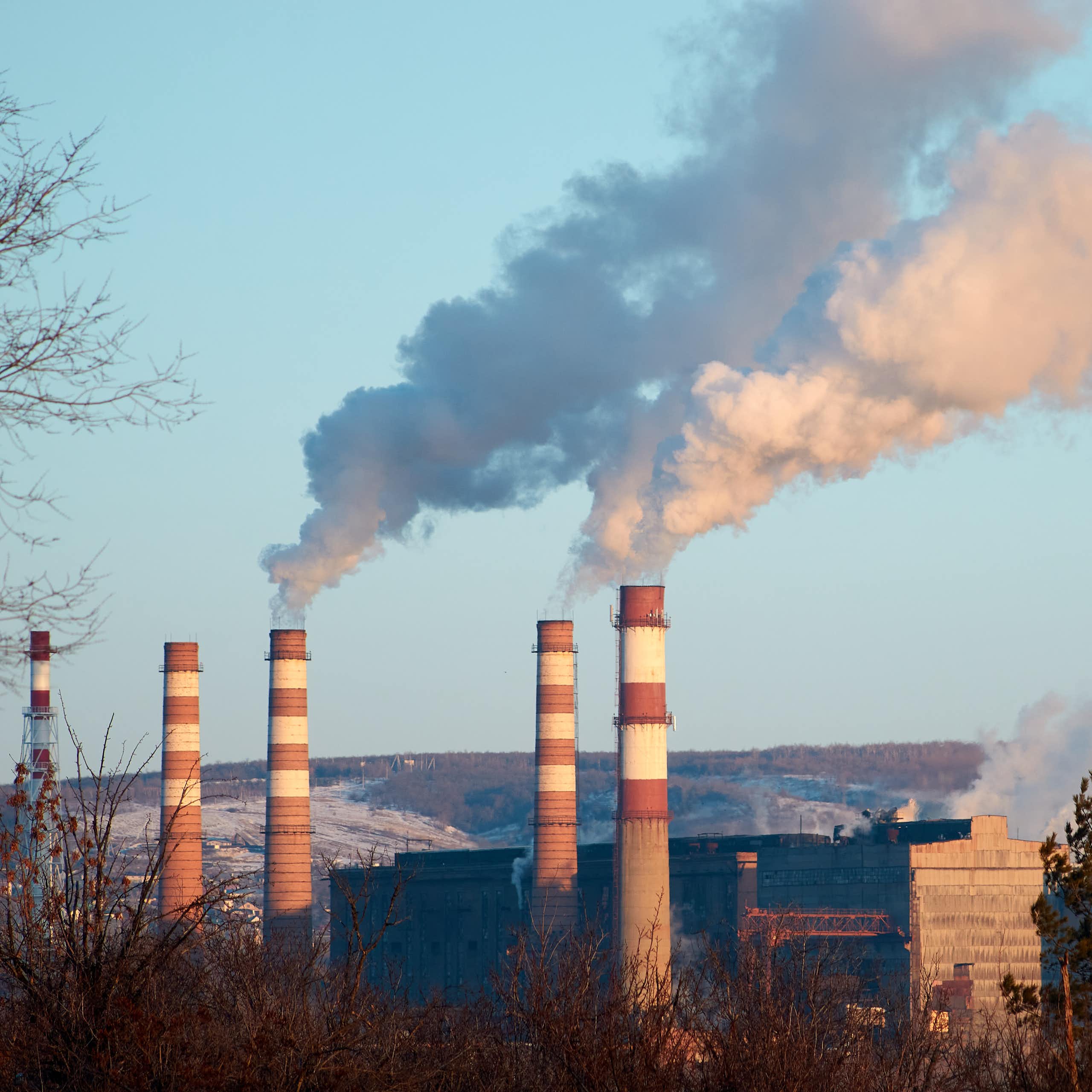 De la fumée sort des cheminées d'une usine pendant une journée ensoleillée, les polluants pénètrent dans l'atmosphère.