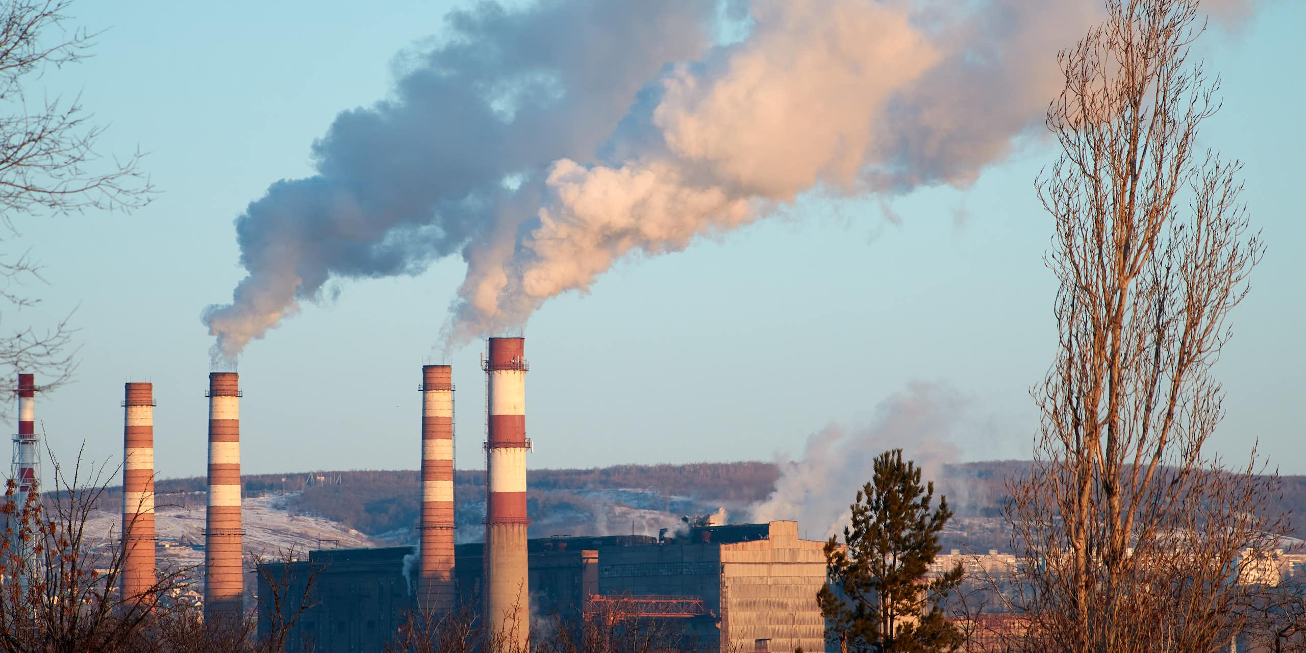 De la fumée sort des cheminées d'une usine pendant une journée ensoleillée, les polluants pénètrent dans l'atmosphère.