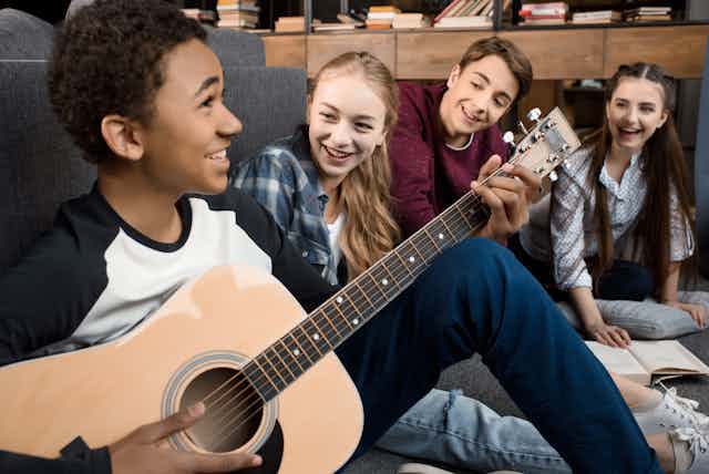 Teenagers playing guitar and listening