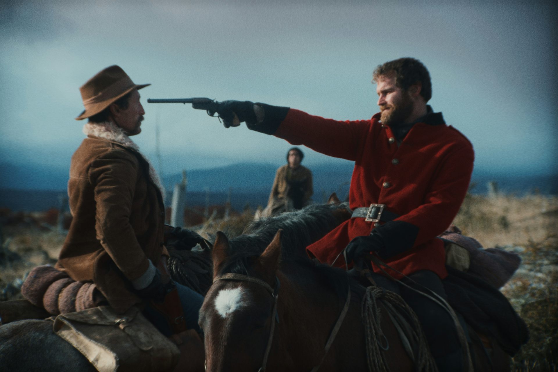 White man points a gun at the head of an indigenous man.