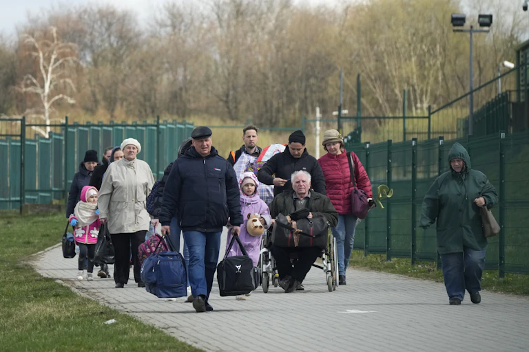 Group of people walk along path between fences
