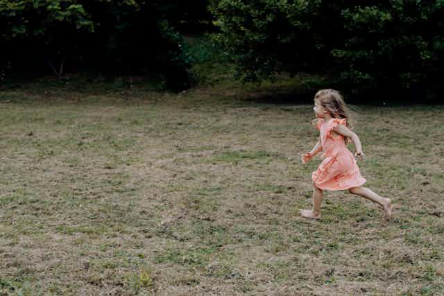 A young girl runs across a lawn