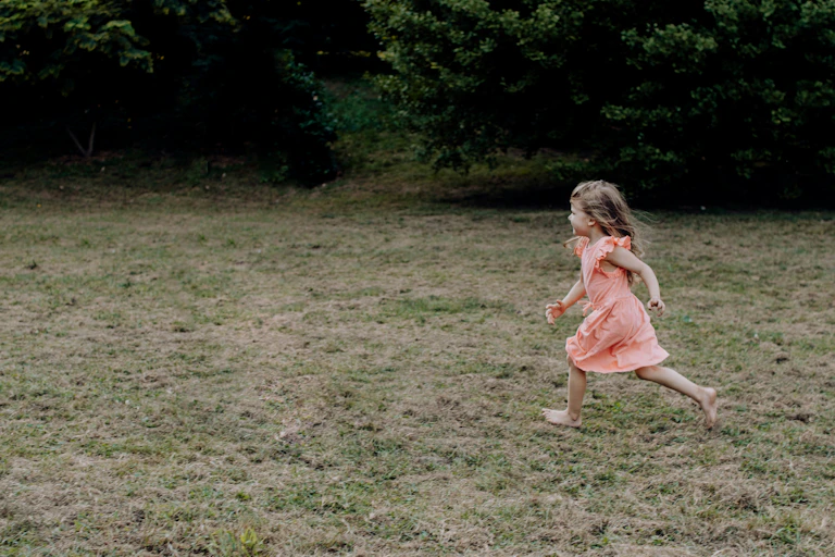 A young girl runs across a lawn