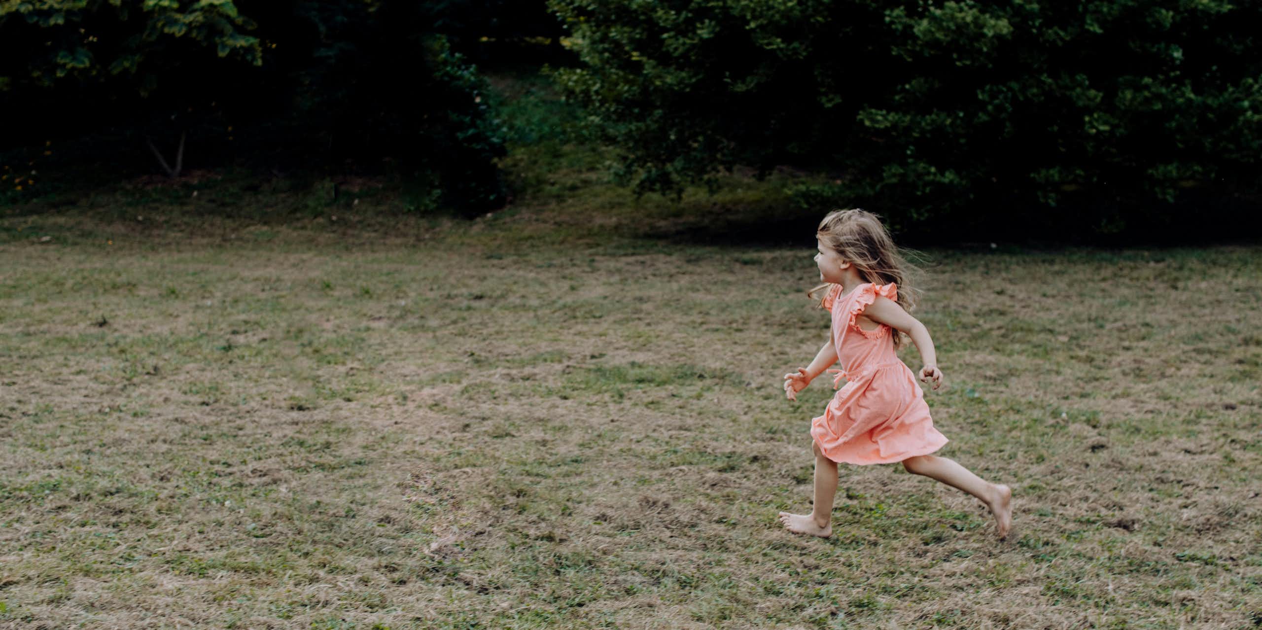 A young girl runs across a lawn