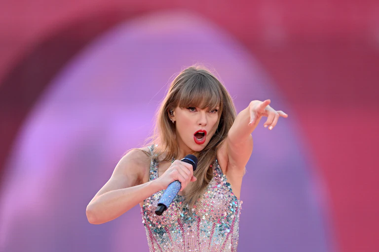 Taylor Swift pointing at the crowd as she performs on stage