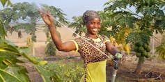 A woman farmer smiles as she turns on her irrigation equipment in Ghana