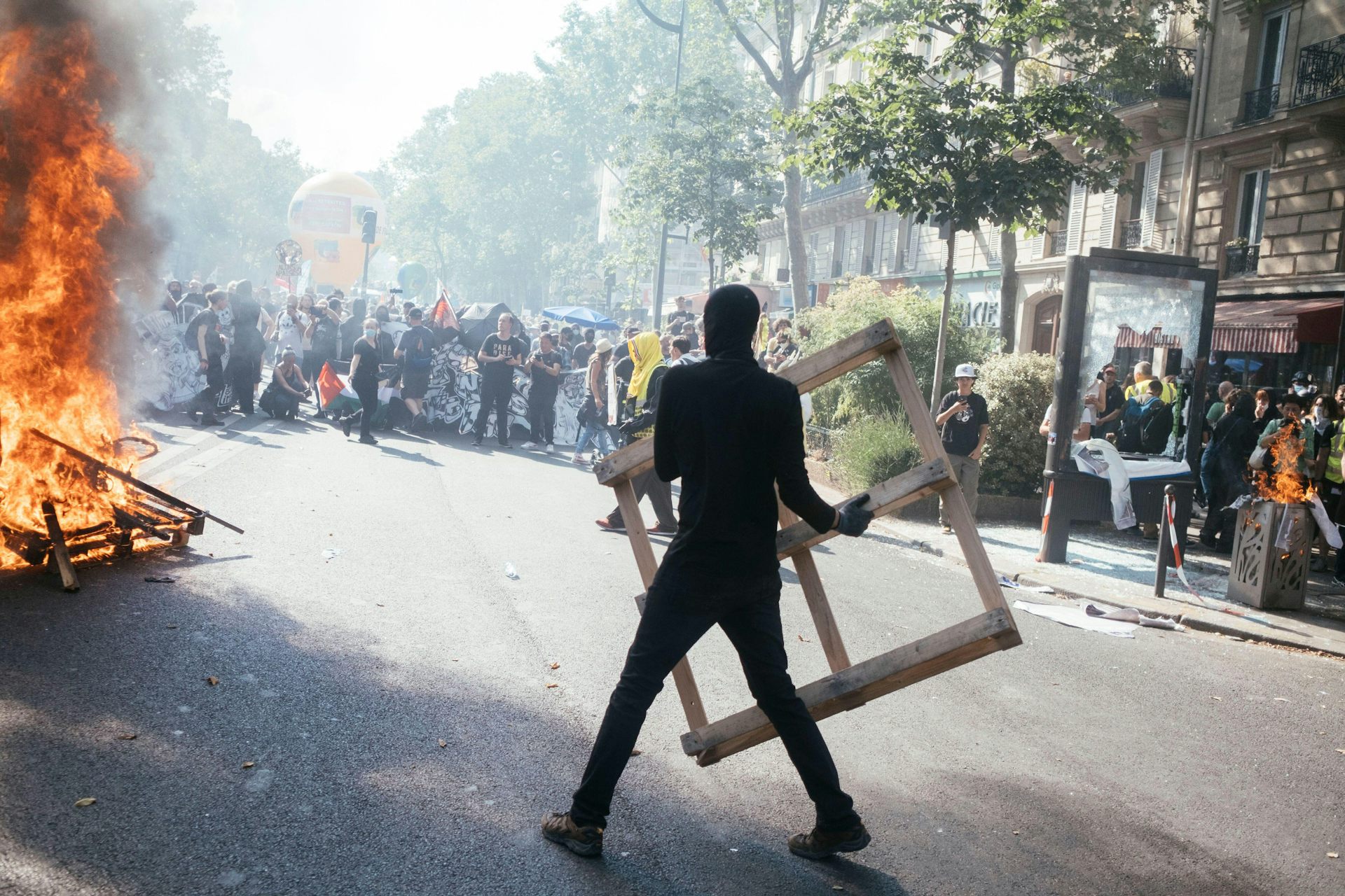 A hooded protester throws objects into a fire during protests against pension reform in France.