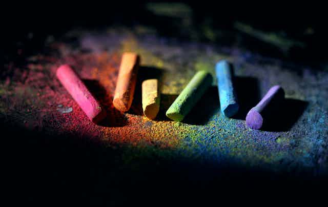 A row of chalk pieces in rainbow colours on the ground.