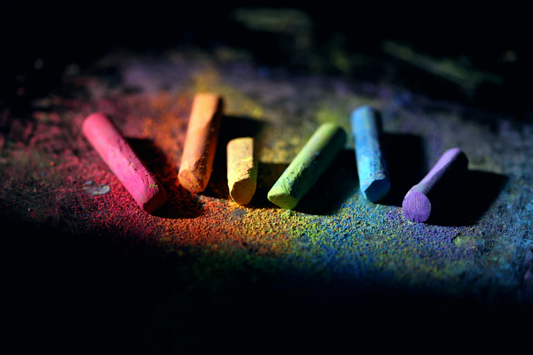 A row of chalk pieces in rainbow colours on the ground.