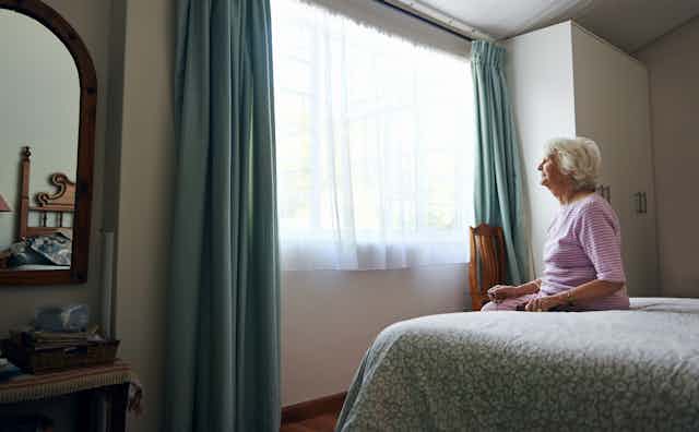 Older woman sits on her bed