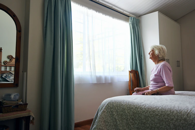 Older woman sits on her bed
