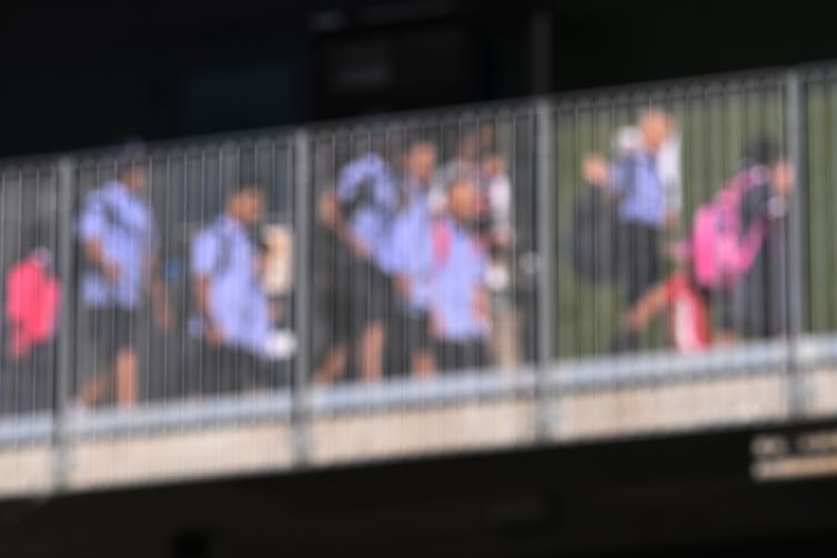 A group of students in uniform walk across a bridge.