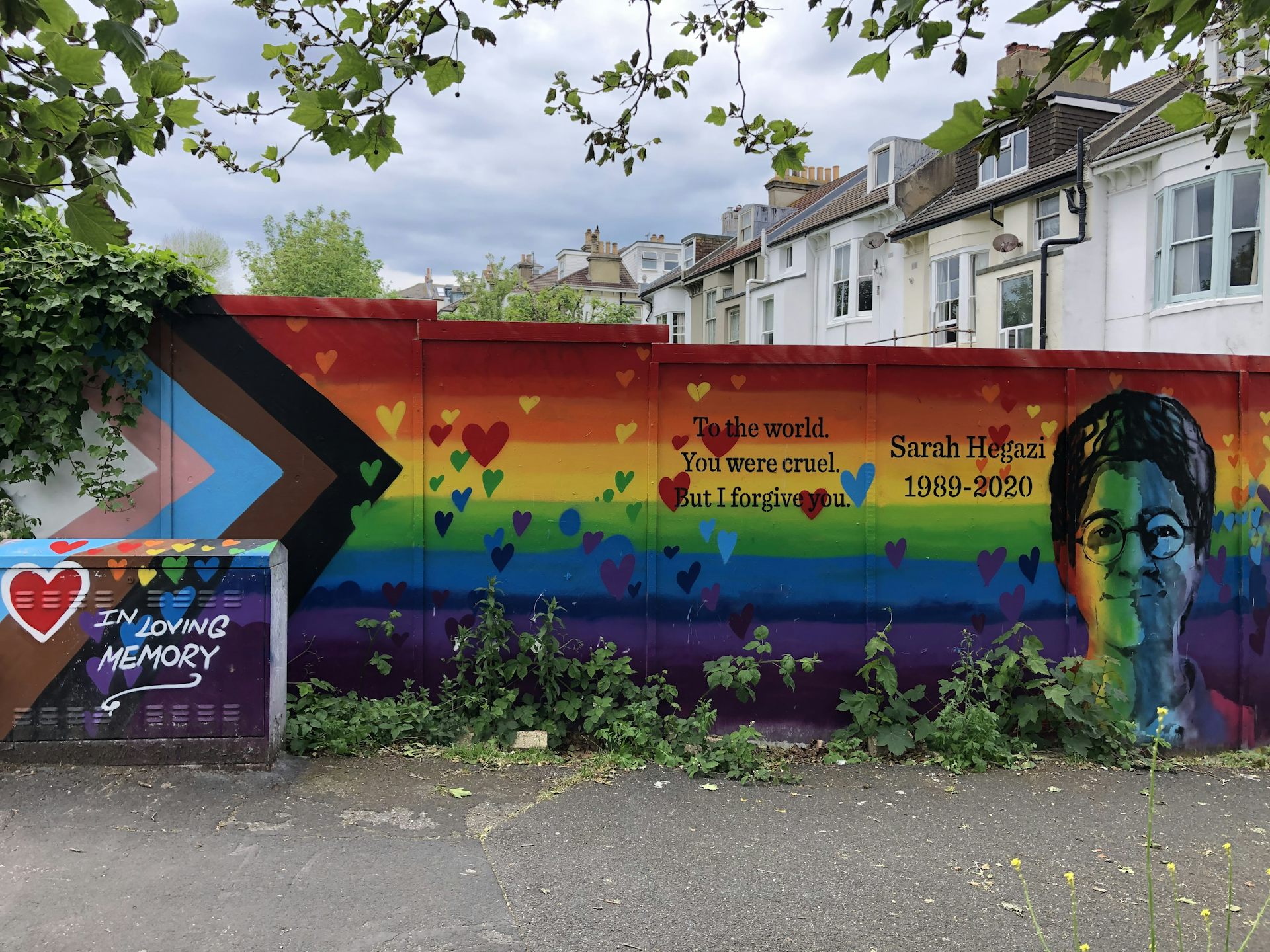 A wall showing a rainbow mural and the face of a young woman.