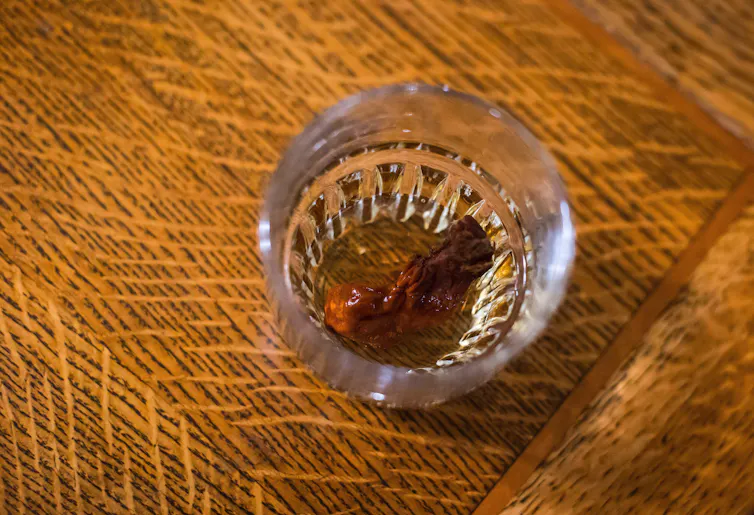 A shot of whisky with a dehydrated human toe in the drink
