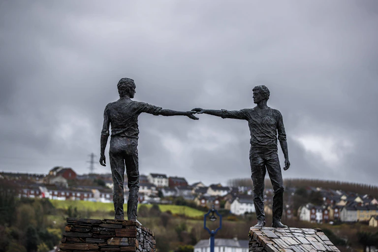 A statue of two men holding out hands across a divide in Northern Ireland.