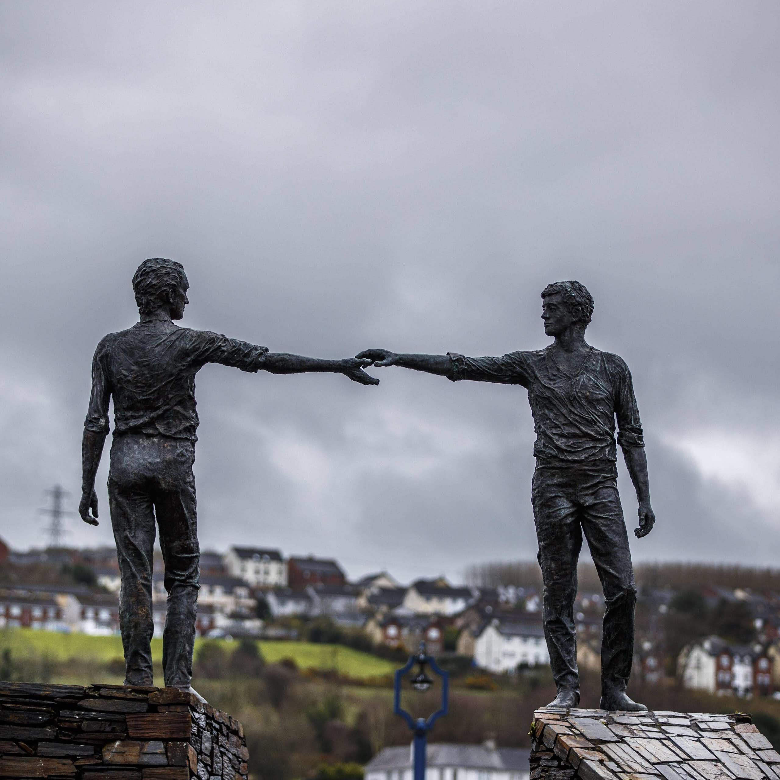 A statue of two men holding out hands across a divide in Northern Ireland. 