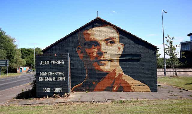 A mural depicting a man in a brown uniform (Alan Turing) on a gable end wall.