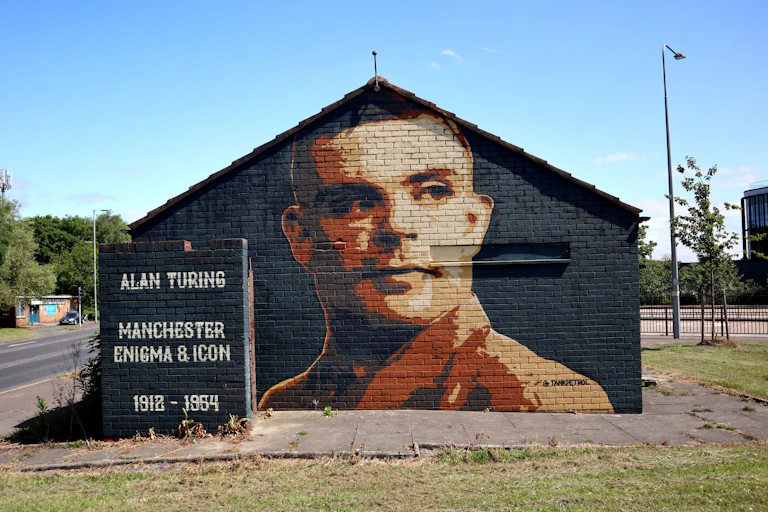 A mural depicting a man in a brown uniform (Alan Turing) on a gable end wall.