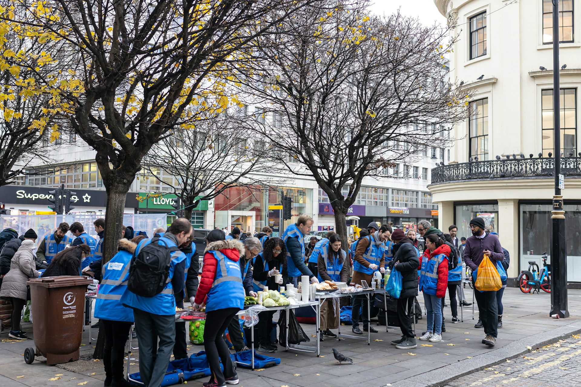 People in blue high-vis vests at a table with food for distribution.