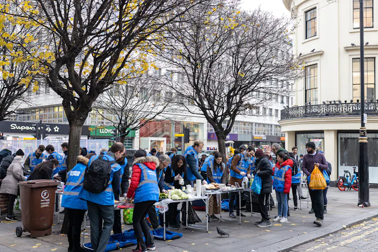 People in blue high-vis vests at a table with food for distribution.