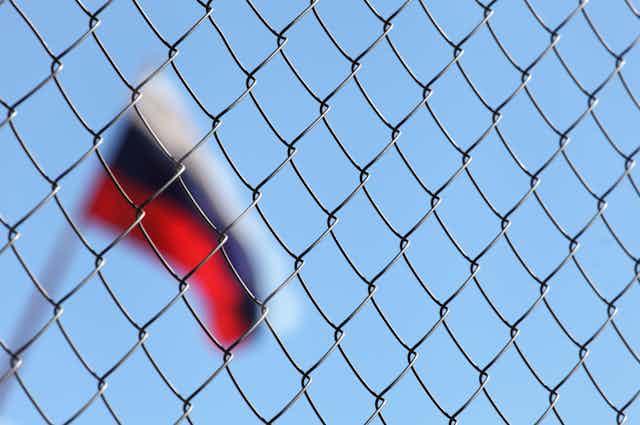 Blurred Russian flag behind wire fence.