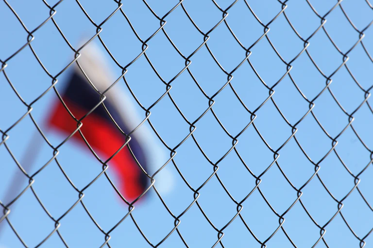 Blurred Russian flag behind wire fence.