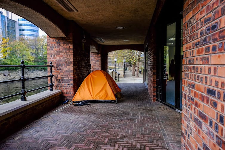 An orange tent under a brick passageway.