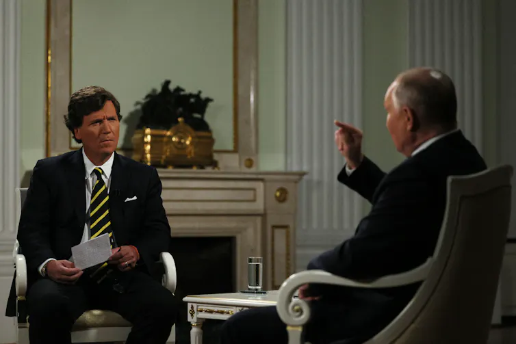 Two men talking in an elegant, high-ceilinged room.